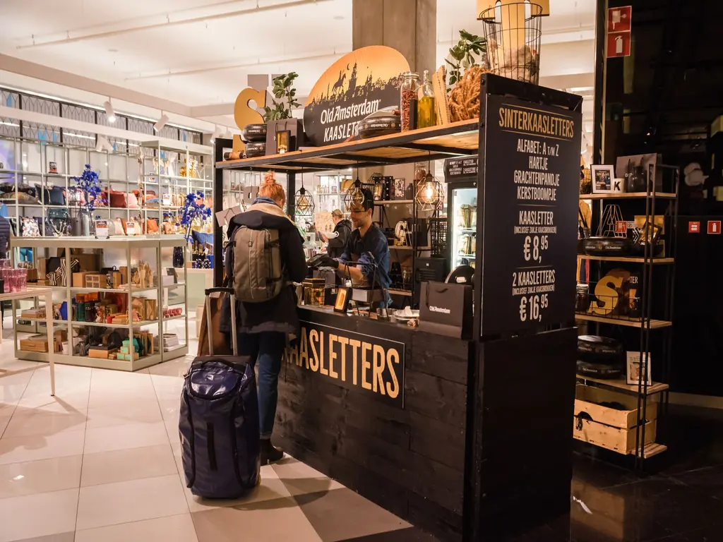 Bezoeker koopt een gepersonaliseerde kaasletter bij de Old Amsterdam pop-upactivatie in een winkelcentrum.