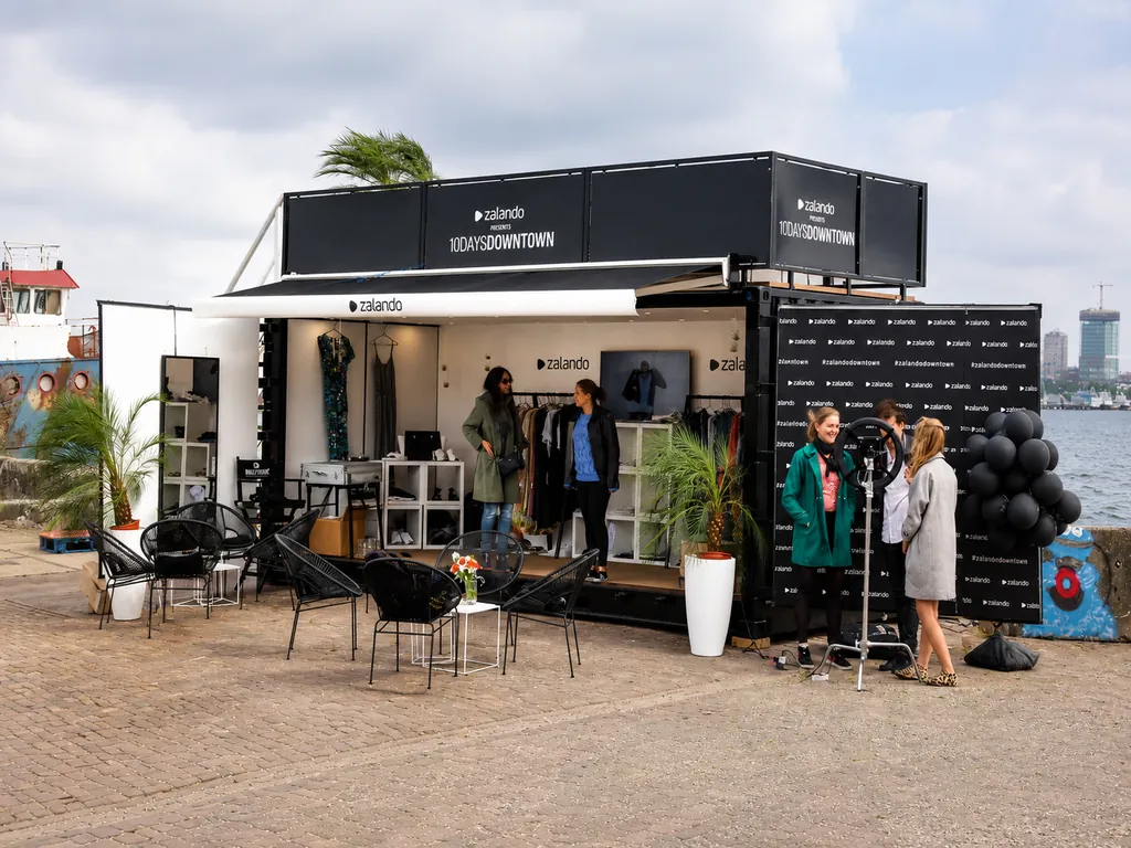 Zalando pop-upstore tijdens Amsterdam Fashion Week met bezoekers en kledingpresentatie aan het water.